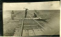 [Four men working on the railroad track]