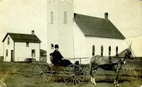 [Man and horse-drawn wagon in front of church]