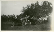 [Students posing around cars]